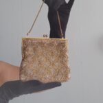 Bolsa de mão vintage de festa bordada manualmente com canutilhos dourados e prateados formando desenho geométrico em losangos, com armação metálica dourada, fecho tipo kiss lock e corrente curta.