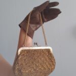 Bolsa de mão vintage original em malha de fio metálico dourado, com armação metálica gravada, fecho tipo kiss lock e alça de corrente dourada, provável produção das décadas de 1950/60