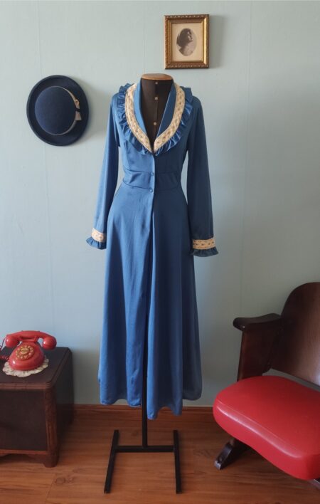Penhoar vintage original dos anos 70 na cor azul com detalhes em renda clara na gola e punhos, modelagem longa e fluida, exposto em manequim em ambiente com decoração retrô.