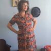 Chemisier vintage original dos anos 70 em jersey de poliamida com estampa floral em tons coral, marrom e bege. Modelo midi com mangas curtas, fechamento frontal por botões e faixa para amarração na cintura. Peça feminina vintage em excelente estado de conservação, fotografada em ambiente interno com decoração retrô.