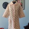 Penhoar vintage original dos anos 70 em matelassê off-white com estampa de pequenos buquês de flores rosa. Modelo com acabamento em viés rosa, bolso frontal arredondado com laço decorativo e estilo delicado e romântico. Peça vintage feminina com sinais do tempo preservando sua beleza original.