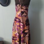 Vestido longo vintage original dos anos 70 com estampa psicodélica em tons de roxo, lilás, bege e amarelo. Modelo de alças finas com aplicações de lantejoulas e caimento fluido. Peça feita por costureira em tecido sintético com forro, fotografada em manequim em ambiente interno com decoração retrô.