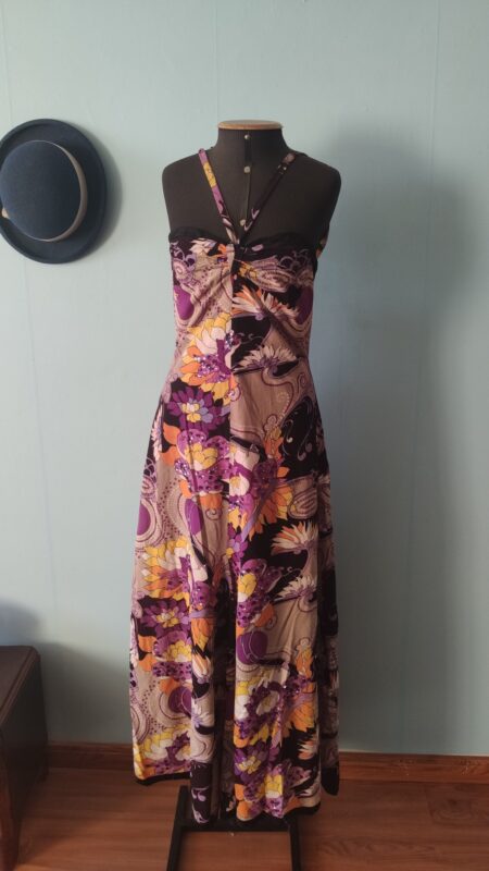 Vestido longo vintage original dos anos 70 com estampa psicodélica em tons de roxo, lilás, bege e amarelo. Modelo de alças finas com aplicações de lantejoulas e caimento fluido. Peça feita por costureira em tecido sintético com forro, fotografada em manequim em ambiente interno com decoração retrô.