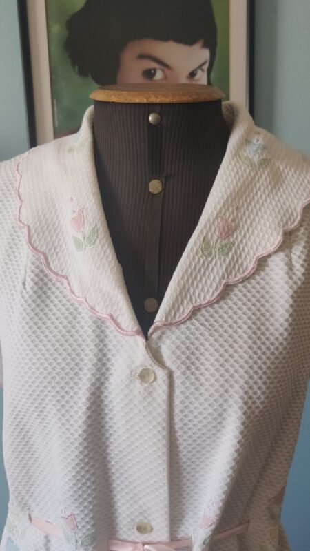Detalhe da gola ondulada com debrum rosa e acabamento em cetim do penhoar vintage.