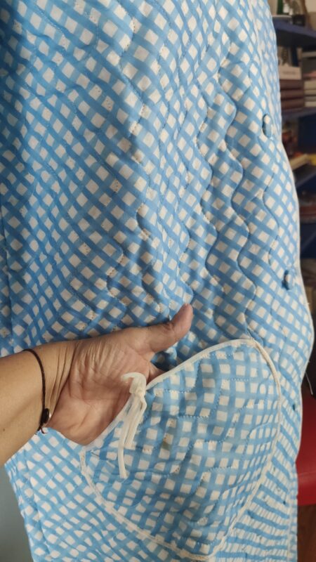 Detalhe do tecido do penhoar vintage azul e branco, mostrando a estampa geométrica, costuras decorativas e acabamento do bolso.