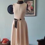Vestido Calvin Klein Dress original em tom off white, com modelagem fit and flare, cintura marcada por fita de gorgurão formando um laço e saia godê. Peça de design minimalista, confeccionada em poliamida e poliéster.