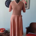 Vestido vintage original dos anos 80 em bouclê salmão, com cintura marcada, saia evasê, mangas curtas e faixa para amarração lateral.