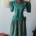 Vestido vintage verde dos anos 80 em tafetá, com mangas volumosas, cintura marcada, grande laço lateral e saia de renda floral.