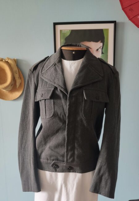 Jaqueta militar vintage cinza chumbo em lã 100%, com lapelas largas, bolsos no peito e modelagem curta.