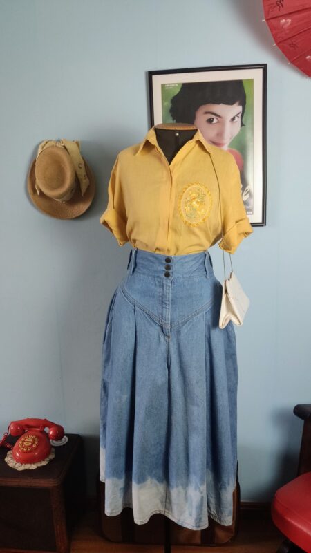 Saia jeans vintage original dos anos 80, azul, de cintura alta e modelagem ampla, combinada com camisa amarela.