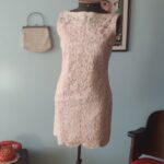Vista frontal de vestido tubinho vintage original dos anos 60 em renda rosa-claro, comprimento mini e modelagem ajustada.
