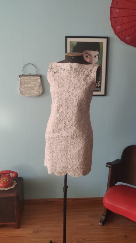 Vista frontal de vestido tubinho vintage original dos anos 60 em renda rosa-claro, comprimento mini e modelagem ajustada.